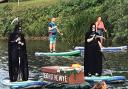 Wild swimmer Angela Jones towing a floating coffin representing the death of the River Wye, accompanied by grim reapers on paddle boards